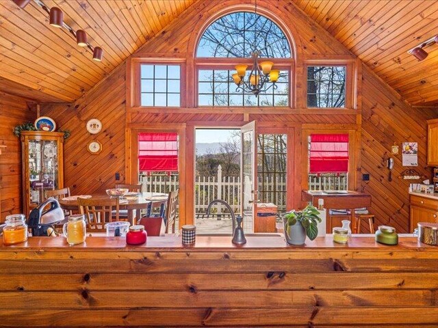 702 John Sevier Dr, Sevierville, TN 37876 - unfurnished living room featuring a chandelier, wood ceiling, high vaulted ceiling, and wooden walls