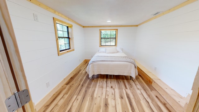 bedroom featuring wood walls and light hardwood / wood-style floors