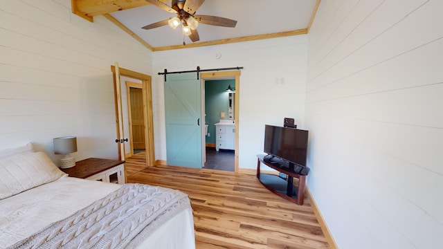 bedroom with wood-type flooring, lofted ceiling with beams, a barn door, and ceiling fan