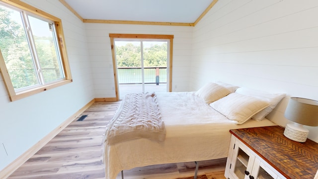 bedroom featuring light wood-type flooring, access to outside, vaulted ceiling, and ornamental molding