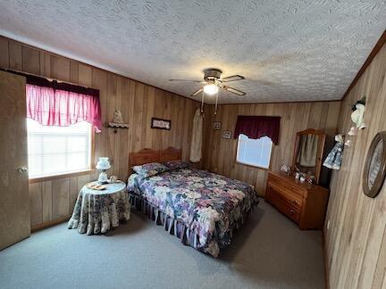 515 Mountain Lake Way, Newport, TN 37821 - carpeted bedroom featuring wood walls, a textured ceiling, and a ceiling fan