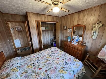 515 Mountain Lake Way, Newport, TN 37821 - bedroom with a textured ceiling, a closet, wooden walls, and a ceiling fan