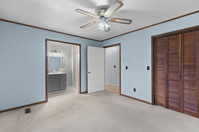 unfurnished bedroom featuring light carpet, ensuite bathroom, sink, ceiling fan, and a closet