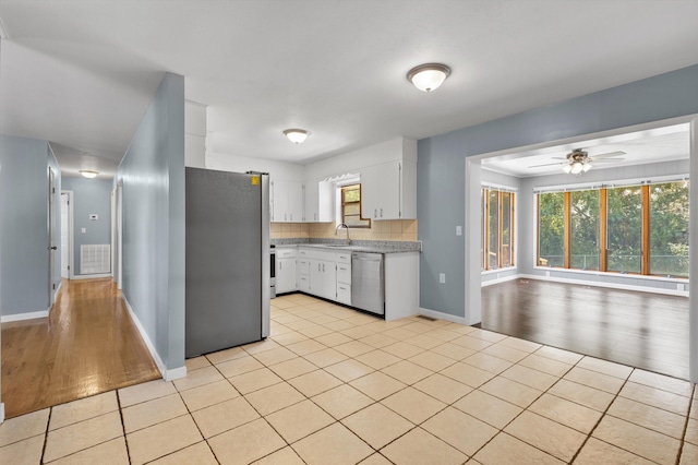 kitchen featuring stainless steel appliances, ceiling fan, sink, light tile patterned floors, and white cabinetry