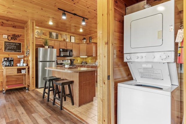 interior space with hardwood / wood-style flooring, stacked washer and clothes dryer, wooden ceiling, and wood walls