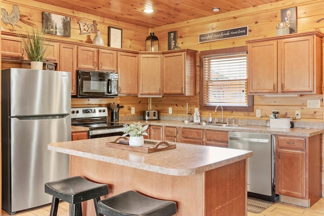 kitchen with sink, wood ceiling, appliances with stainless steel finishes, wooden walls, and an island with sink