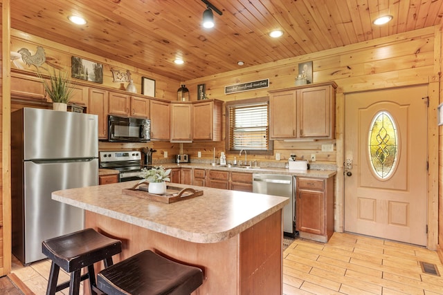 kitchen featuring sink, a breakfast bar area, appliances with stainless steel finishes, a center island, and wooden ceiling