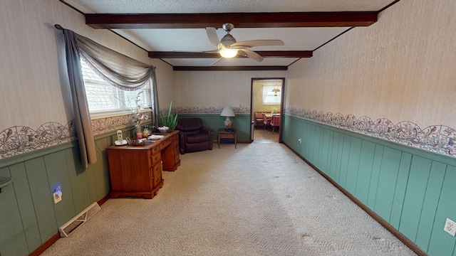 living area with beamed ceiling, light colored carpet, and a textured ceiling