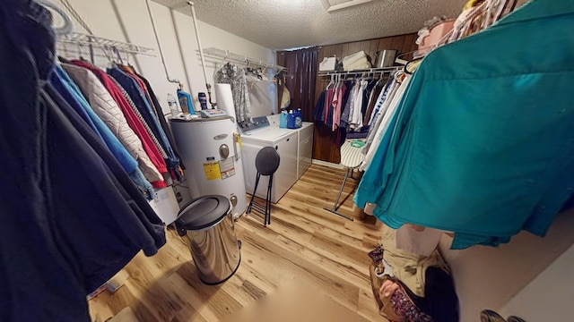 walk in closet featuring washing machine and clothes dryer, light hardwood / wood-style floors, and water heater