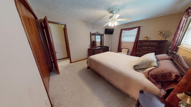 bedroom featuring ceiling fan, light colored carpet, and a textured ceiling