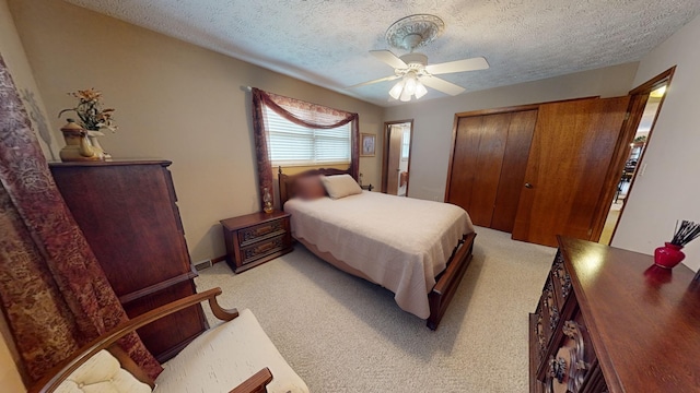 carpeted bedroom with ceiling fan, a textured ceiling, and a closet