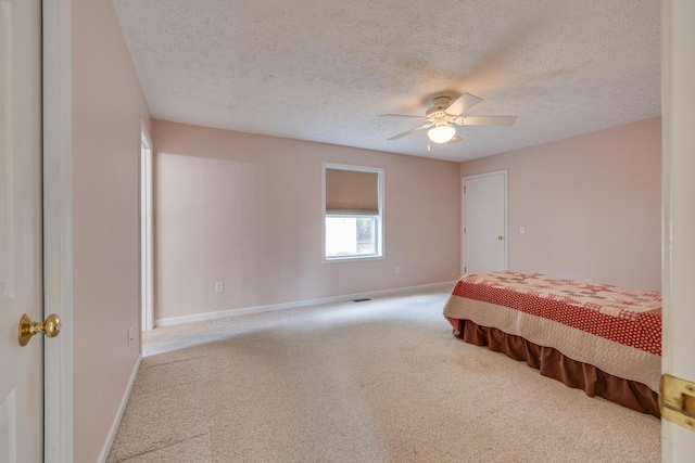 bedroom with ceiling fan, light carpet, and a textured ceiling