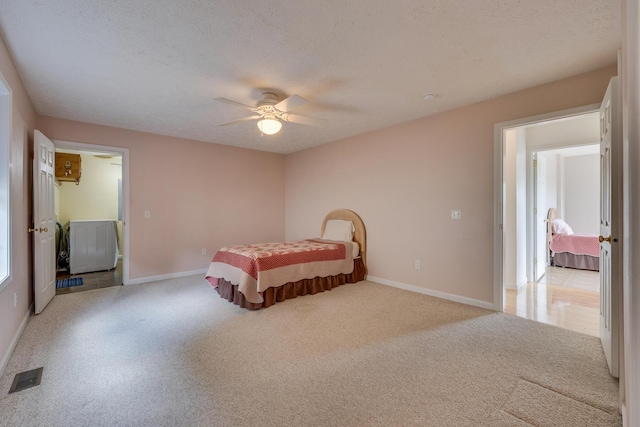 bedroom with ceiling fan, light carpet, and a textured ceiling