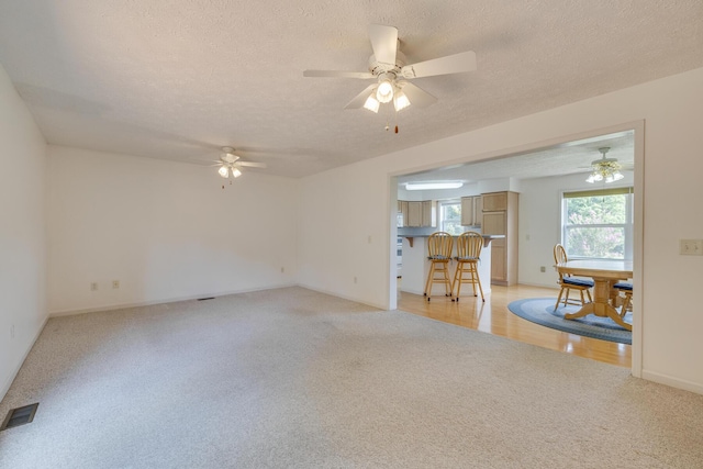 unfurnished room with ceiling fan, light carpet, and a textured ceiling