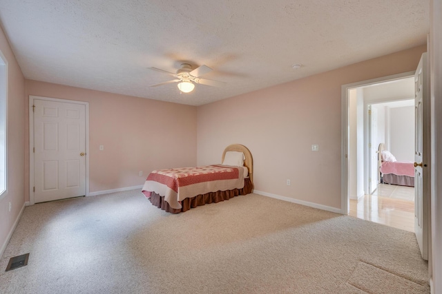 carpeted bedroom with ceiling fan and a textured ceiling