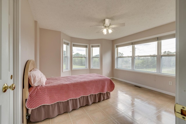 bedroom with ceiling fan and a textured ceiling