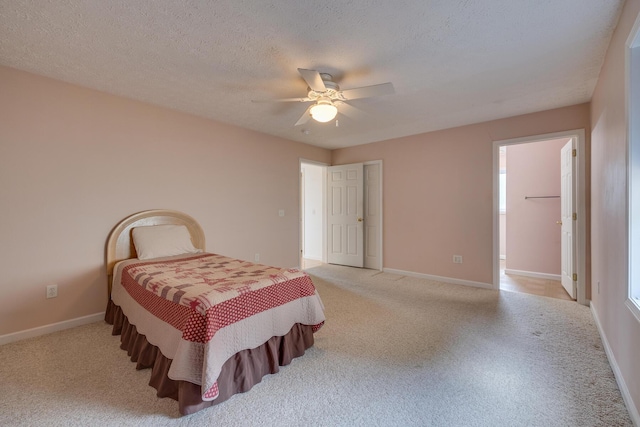 bedroom featuring ceiling fan, light colored carpet, and a textured ceiling