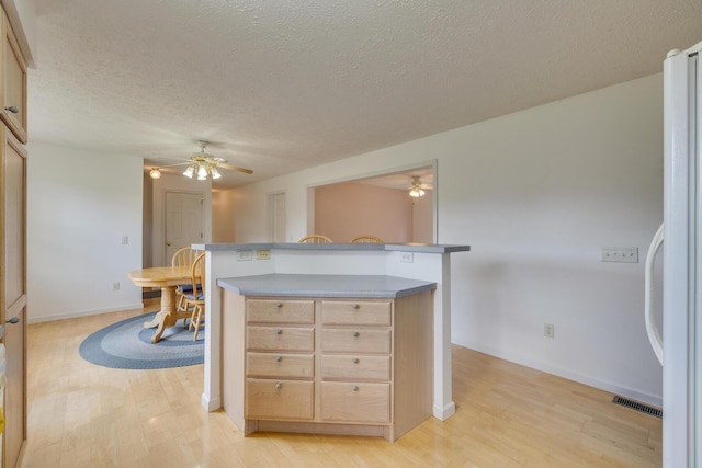 kitchen featuring white refrigerator, a textured ceiling, light hardwood / wood-style flooring, and light brown cabinets