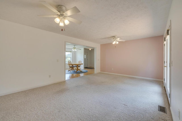 unfurnished living room with ceiling fan, light colored carpet, and a textured ceiling