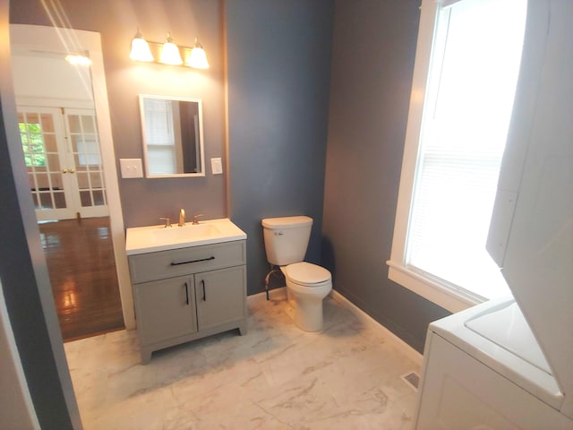 bathroom featuring washer / clothes dryer, french doors, vanity, and toilet