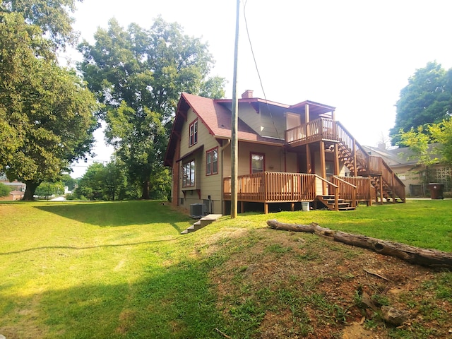 back of property with a deck, a yard, and central AC