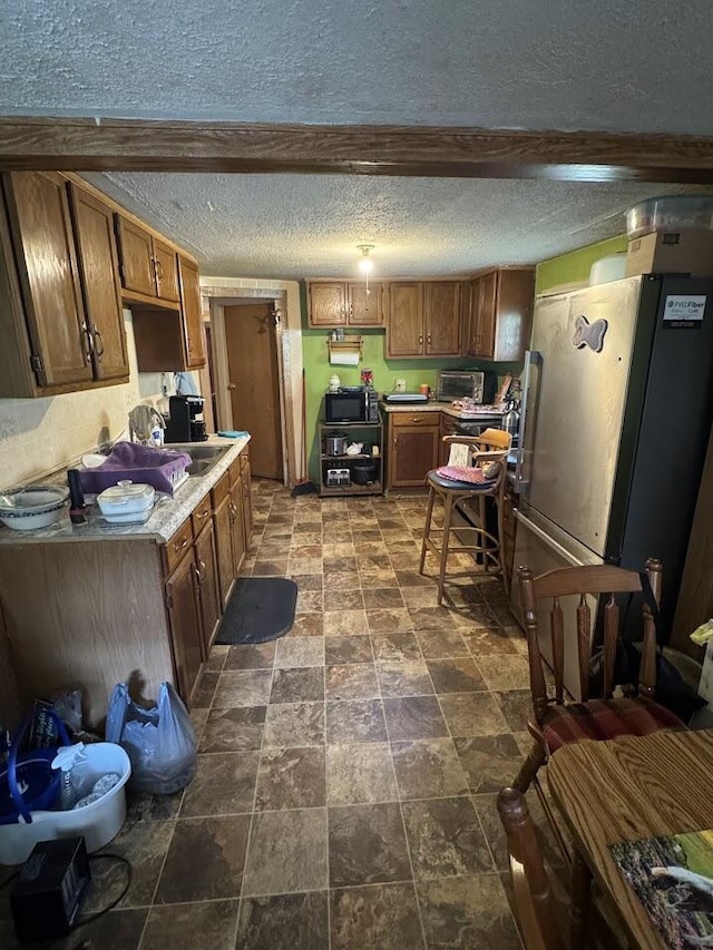 kitchen featuring beam ceiling, a textured ceiling, and fridge