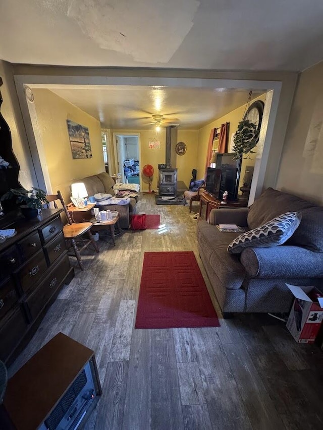 living room with a wood stove, ceiling fan, and wood-type flooring