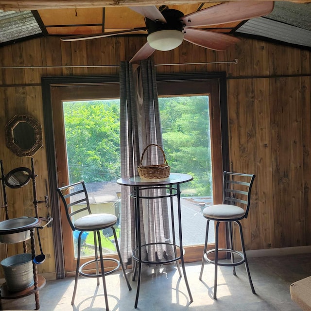 dining room featuring lofted ceiling and wooden walls