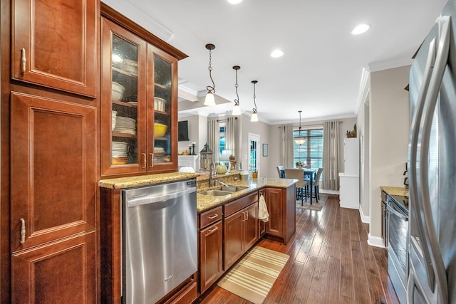 kitchen featuring light stone countertops, sink, decorative light fixtures, appliances with stainless steel finishes, and ornamental molding