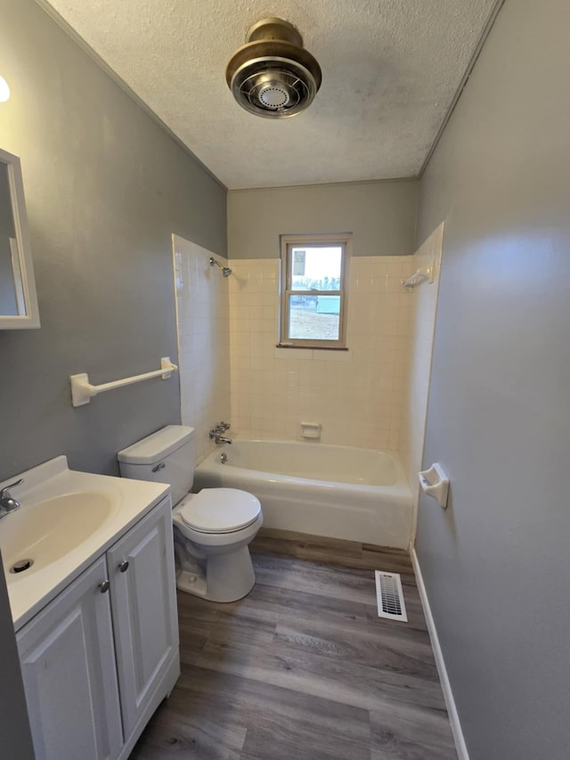 full bathroom with vanity, hardwood / wood-style floors, a textured ceiling, and tiled shower / bath combo