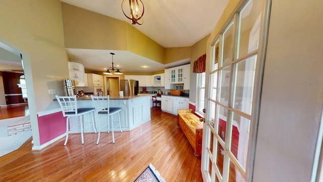 4119 Azalea Ct, Morristown, TN 37814 - kitchen with freestanding refrigerator, a peninsula, a breakfast bar, glass insert cabinets, and light wood finished floors
