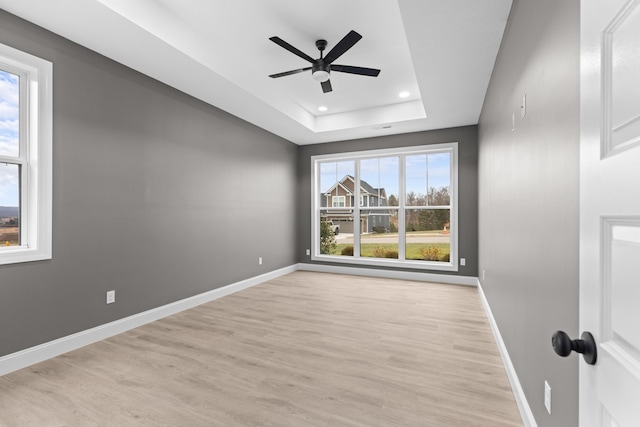 spare room featuring a raised ceiling, ceiling fan, and light hardwood / wood-style floors