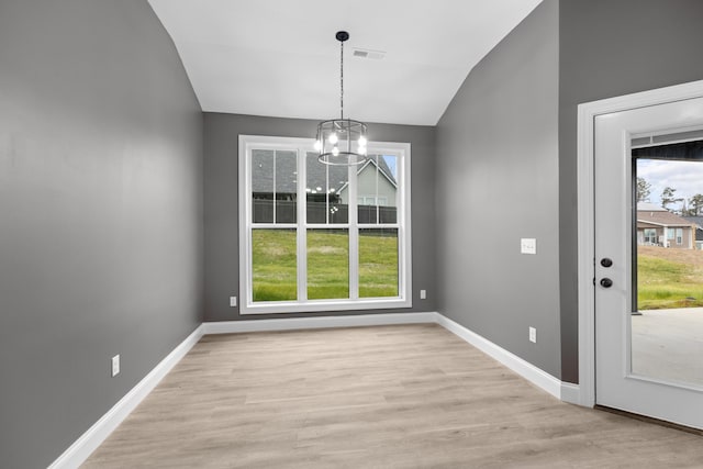 unfurnished dining area with light wood-type flooring, a healthy amount of sunlight, vaulted ceiling, and an inviting chandelier