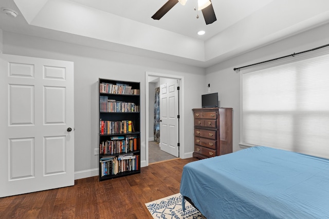 bedroom featuring dark hardwood / wood-style flooring, a raised ceiling, and ceiling fan