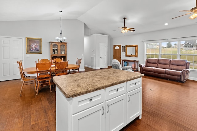 kitchen with dark hardwood / wood-style flooring, ceiling fan with notable chandelier, vaulted ceiling, pendant lighting, and white cabinets