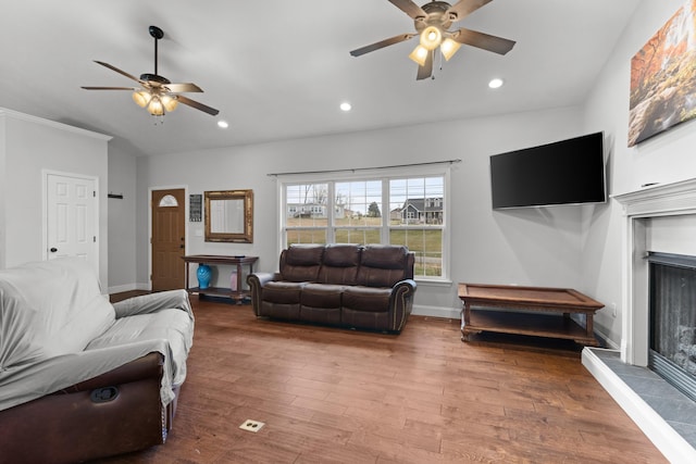 living room with a tiled fireplace, ceiling fan, and hardwood / wood-style floors