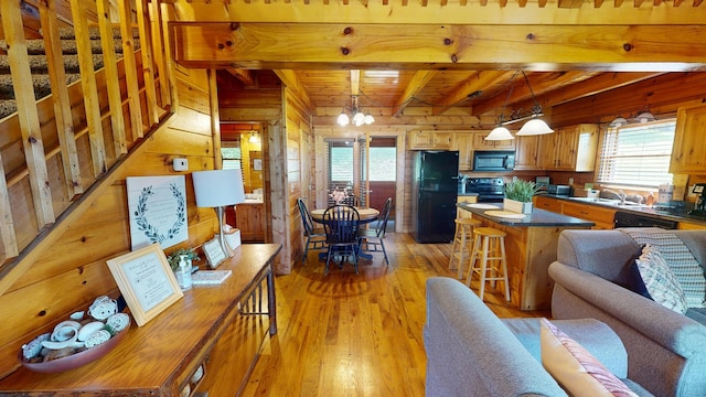 living area with a notable chandelier, beam ceiling, light wood finished floors, wood walls, and wood ceiling