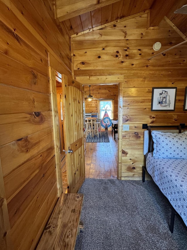 bedroom featuring carpet flooring, vaulted ceiling with beams, and wooden walls