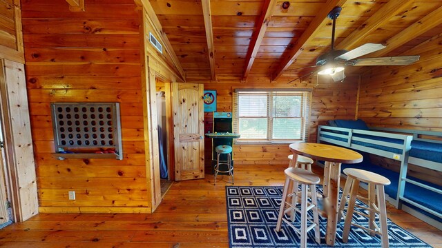 bedroom with wood walls, wooden ceiling, beamed ceiling, visible vents, and hardwood / wood-style flooring