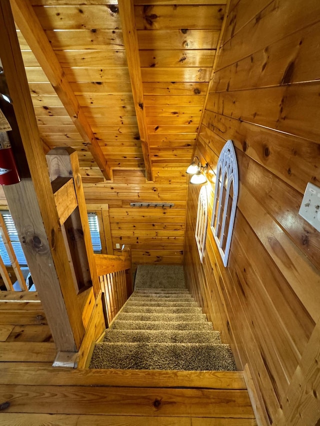 stairway with beam ceiling, wooden ceiling, and wooden walls