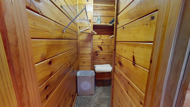 hall featuring wood-type flooring, wood walls, lofted ceiling with beams, and visible vents