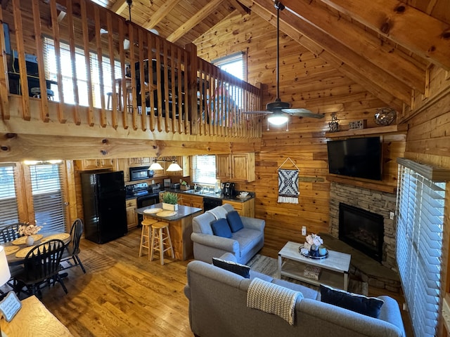 living area featuring light wood-style floors, wooden ceiling, wood walls, and beamed ceiling