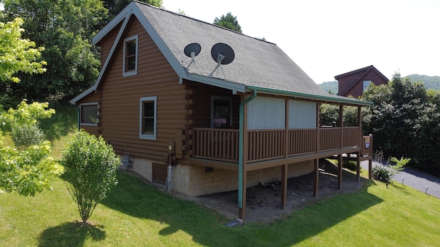 exterior space with a yard, a deck, log siding, and roof with shingles