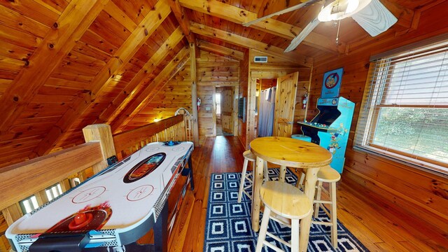 game room featuring wooden walls, wood-type flooring, a ceiling fan, vaulted ceiling with beams, and wood ceiling