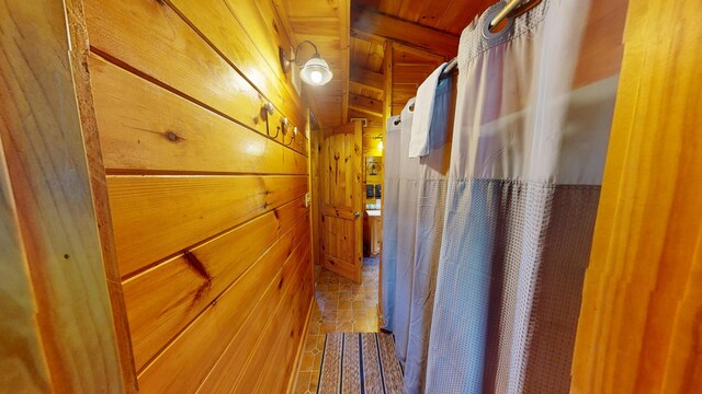 hallway with tile patterned floors and wood walls