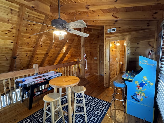 recreation room with lofted ceiling with beams, wooden ceiling, hardwood / wood-style flooring, wooden walls, and visible vents