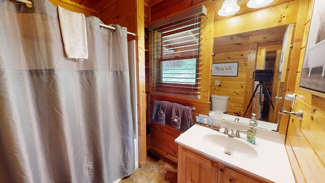 bathroom with curtained shower, vanity, tile patterned floors, toilet, and wooden walls