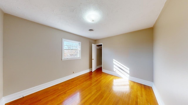 unfurnished room featuring light hardwood / wood-style floors and a textured ceiling