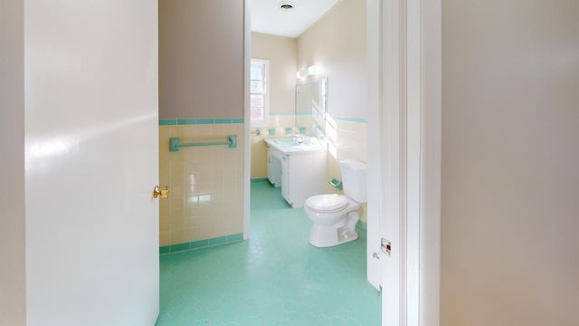 bathroom with vanity, toilet, and tile walls