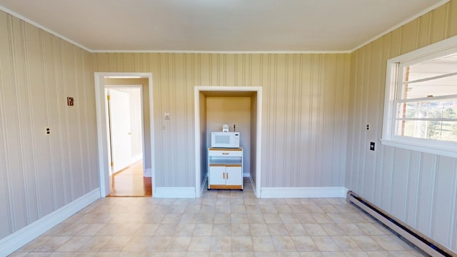 empty room with crown molding and a baseboard heating unit